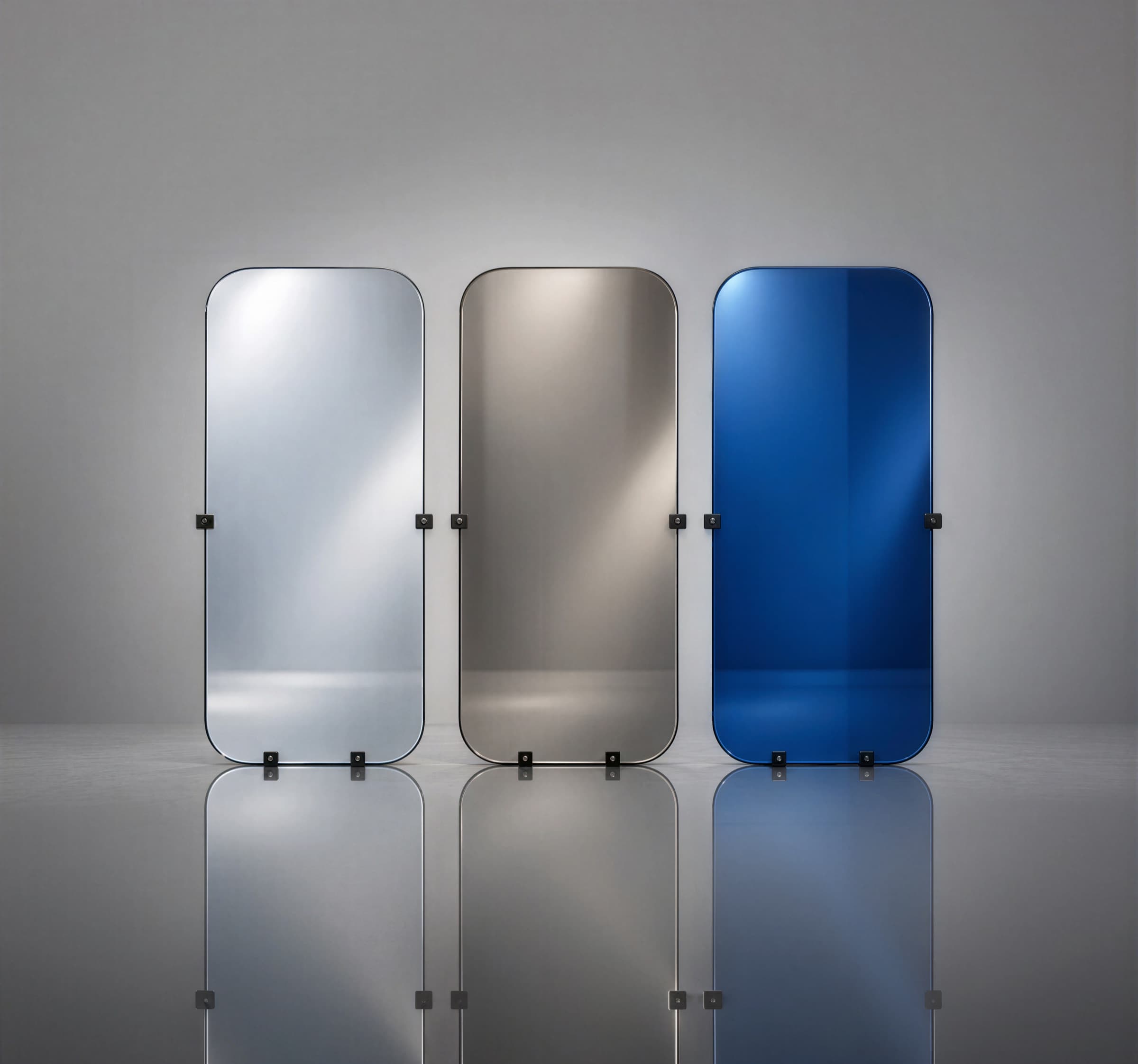 Three coated glass panels in silver, bronze, and blue reflective finishes, standing on a reflective floor