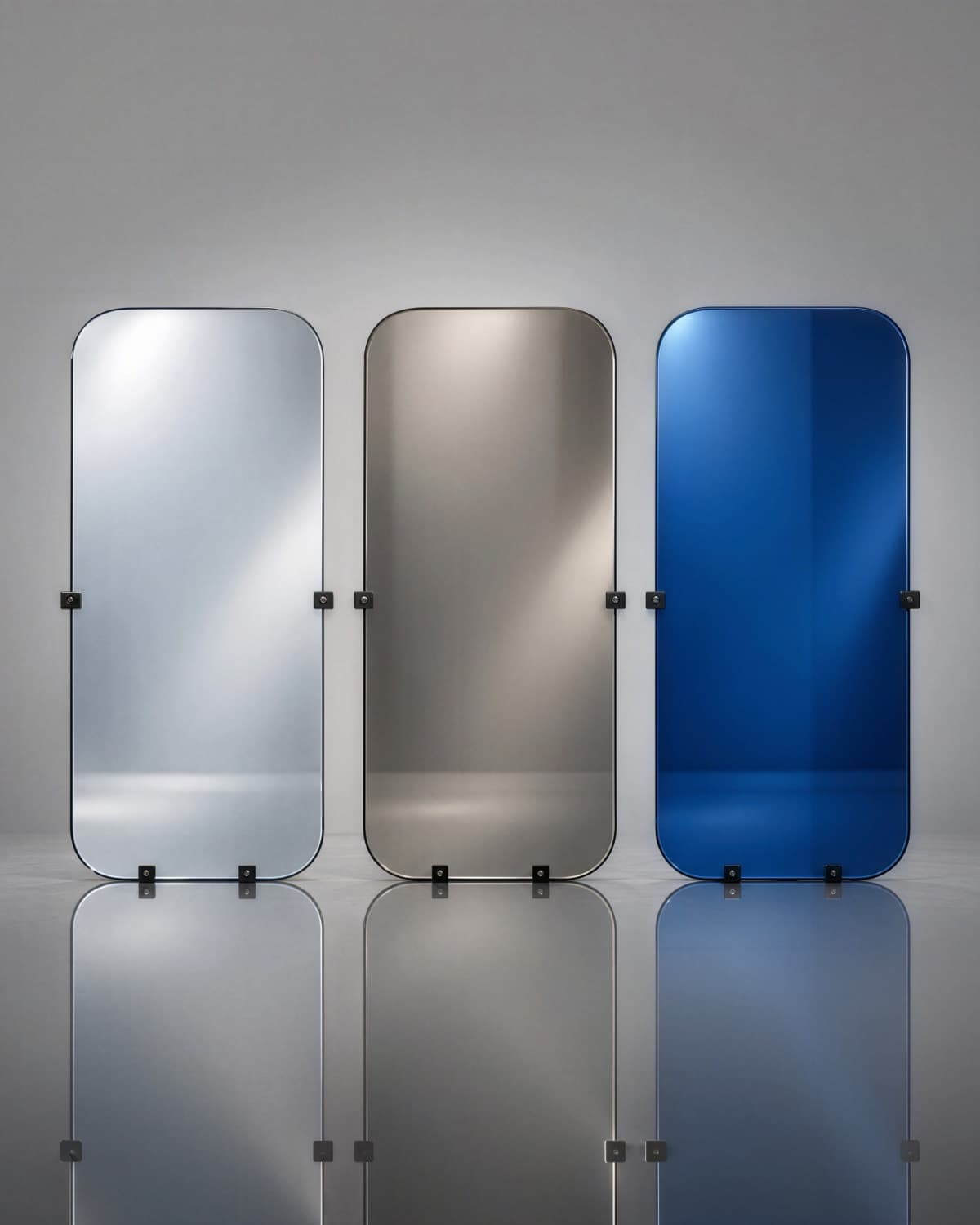 Three coated glass panels in silver, bronze, and blue reflective finishes, standing on a reflective floor